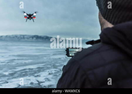 Sur l'épaulement tourné de caucasien homme battant quadcopter gelés sur le lac de l'Utah, USA Banque D'Images