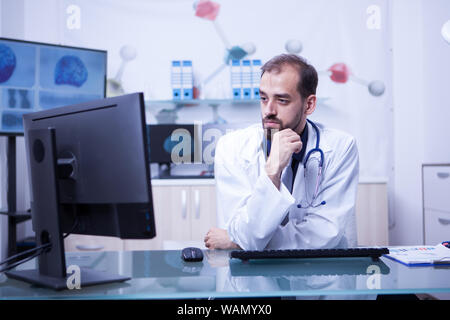 Portrait d'une jeune médecin à la recherche dans le moniteur dans son cabinet. Médecin à l'aide de son ordinateur pour travailler. Banque D'Images