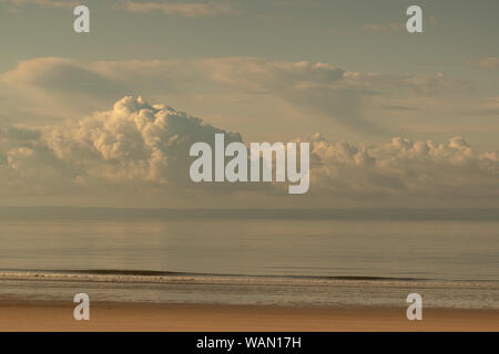 Fluffy clouds gonflée par le bas sur une marée basse à plage de Swansea, Pays de Galles, Royaume-Uni Banque D'Images