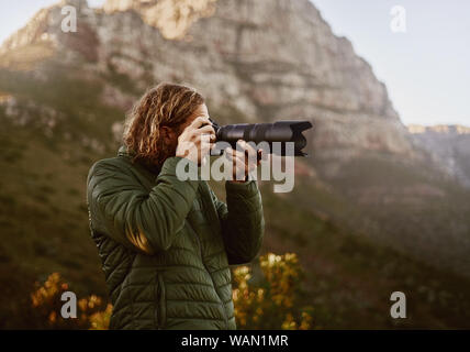 Jeune homme photographe en cliquant sur la photo de votre appareil photo reflex numérique Banque D'Images