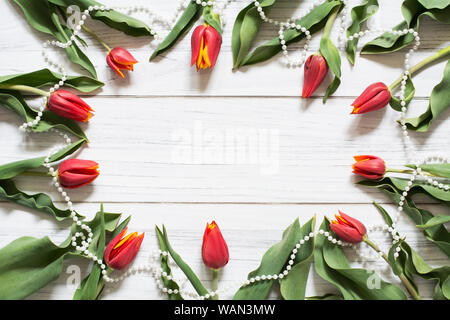 Frontière avec printemps tulipes rouges et blancs de la chaîne de perles disposées en cercle sur fond de bois blanc Banque D'Images