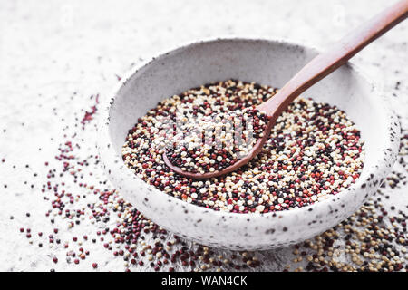 Noir, rouge et blanc les grains de quinoa sur fond gris. Alimentation saine. Banque D'Images