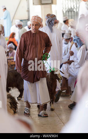 L'homme de prendre des chèvres à vendre sur Sinaw, marché de l'Oman Banque D'Images