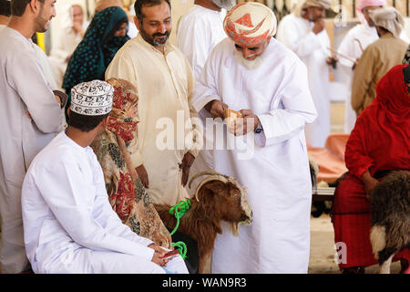 Les hommes et les femmes en vêtements traditionnels une chèvre trading marché Sinaw, Oman Banque D'Images