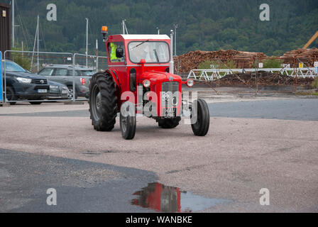 Man Driving 1962 Vintage Rouge Blanc modèle Massey Ferguson 290 Tracteur à cabine avant les pilotes masculins hors-jeu vue du côté de la calandre en fer à cheval Sandpoint Marina 1 Banque D'Images