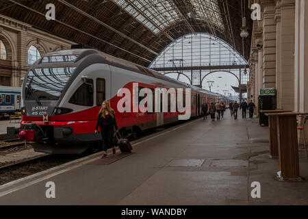 Fille avec une valise qui s'éloignent d'un train à la gare Keleti de Budapest. Banque D'Images