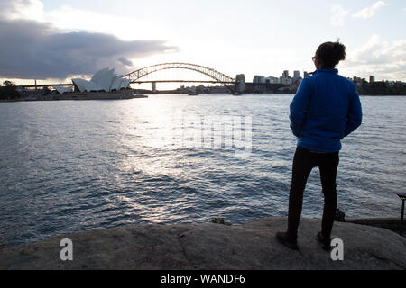 Un homme pendant le coucher du soleil, la fixant à l'Opéra de Sydney Banque D'Images