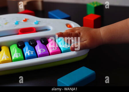Bébé jouer et apprendre avec un piano jouet. Banque D'Images