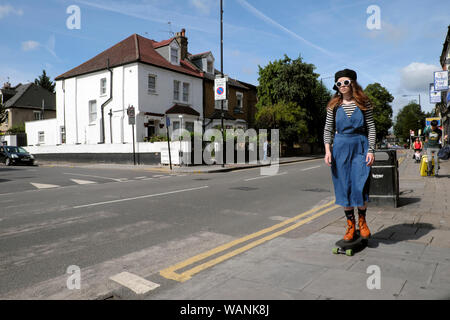 Teen élégant jeune femme portant des lunettes de soleil et bottes rouge sur roulettes dans la rue de l'ouest de la Route Verte dans sept Sœurs Tottenham London N16 UK KATHY DEWITT Banque D'Images