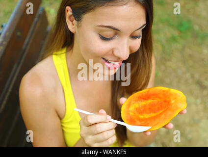 Fille d'une alimentation saine la papaye dans le parc. Woman eating fruits tropicaux frais à l'extérieur. Banque D'Images