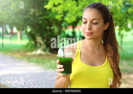 Sporty woman looking at sa green smoothie détox avec copie espace. Banque D'Images