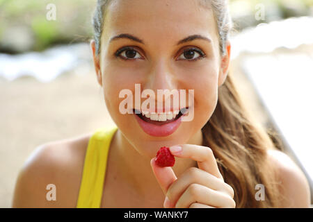 Close up of beautiful girl eating fruits rouges à l'extérieur. Banque D'Images