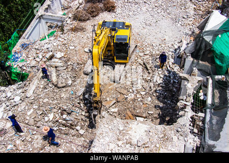 Les machines de la pelleteuse travaillant sur le site de la démolition d'un vieux building workers pulvériser de l'eau pour se débarrasser de la poussière. Banque D'Images