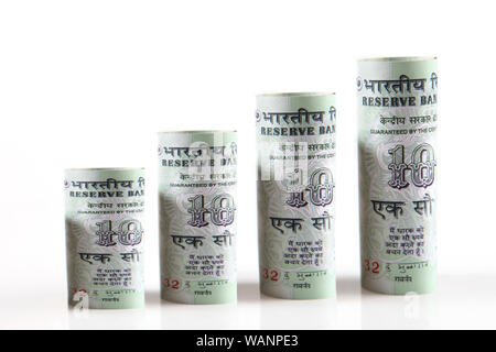Rouleaux de cent billets de roupie disposés en forme de graphique à barres en progression, isolés sur fond blanc Banque D'Images
