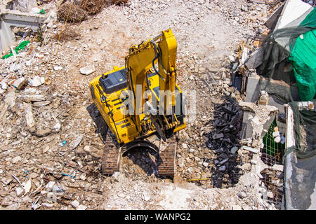 Les machines de la pelleteuse travaillant sur le site de la démolition d'un vieux building workers pulvériser de l'eau pour se débarrasser de la poussière. Banque D'Images