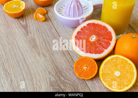 Still Life - divers ensemble et couper les agrumes, l'aléseur manuel et verre de jus d'orange sur une table en bois Banque D'Images