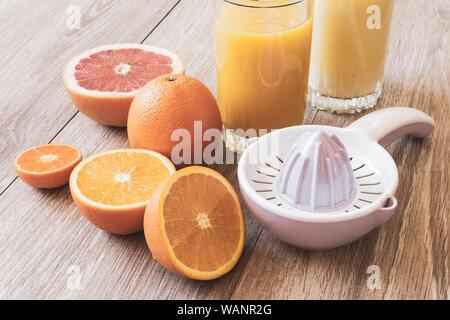 Still Life - divers ensemble et couper les agrumes, l'aléseur manuel et verre de jus d'orange sur une table en bois en couleurs pastel Banque D'Images