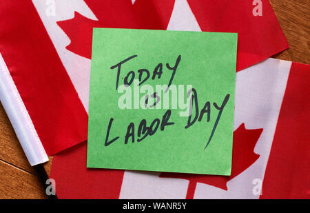 Aujourd'hui est le jour de travail écrit sur un post-it vert, la note est couché sur des drapeaux canadiens Banque D'Images