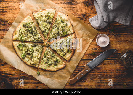 Tranches de pizza italienne avec brocoli, sauce pesto, herbes et parmesan sur du papier sulfurisé. Vue de dessus Banque D'Images