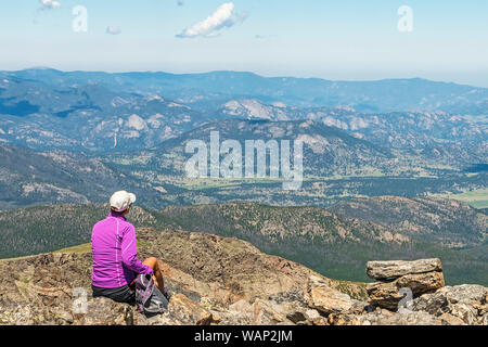 Un female hiker regarde vers les vallées du Parc National des Montagnes Rocheuses au repos le long de la Flattop Mountain Trail. Banque D'Images