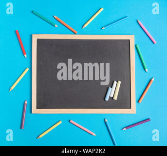 Blank chalkboard et crayons de couleur sur un fond bleu. Retour à l'école télévision concept laïcs Banque D'Images