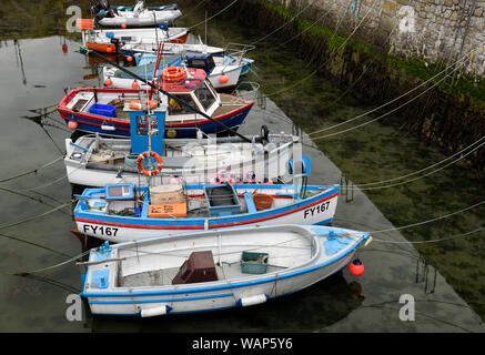 Ligne de bateaux de pêche amarrés au quai de pierre de port à marée basse de Porthleven Angleterre Cornwall Banque D'Images