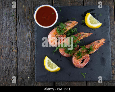 Les crevettes bouillies de citrons verts, la sauce et sur un fond de bois. Vue d'en haut Banque D'Images