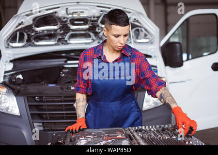 Femme travaille dans la réparation de voiture vérifier si elle dispose de tous les instruments qu'elle pourrait avoir besoin pour son travail. Banque D'Images