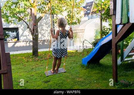 3-5 ans fille blonde s'amusant sur une balançoire à l'extérieur. Jeux d'été. Fille se balançant de haut. Jeune enfant sur la balançoire dans le jardin