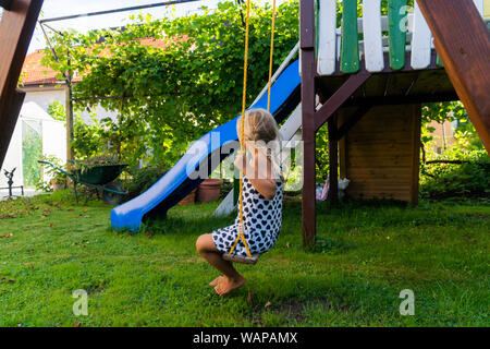 3-5 ans fille blonde s'amusant sur une balançoire à l'extérieur. Jeux d'été. Fille se balançant de haut. Jeune enfant sur la balançoire dans le jardin Banque D'Images