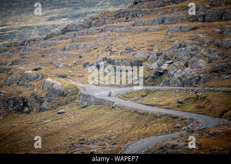 Lone motorcyclist descend le col Healy comme il serpente le long de la vallée sur la péninsule de Beara dans le comté de Cork en Irlande Banque D'Images