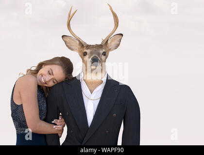 Smiling teenage girl with big buck deer in tuxedo costume isolé sur fond rose blush doux Banque D'Images