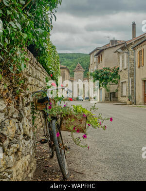 Feneyrols, Midi Pyrénées, France - 23 juillet 2017 : vue frontale d'un vieux vélo décoré de fleurs avec un clocher au bas de la rue Banque D'Images