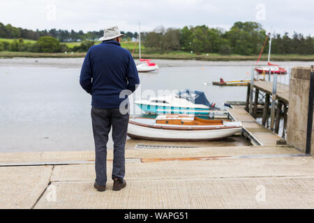 Un seul male debout sur le bord d'un quai et à la recherche sur la rivière et les bateaux qui sont amarrés jusqu'a proximité Banque D'Images