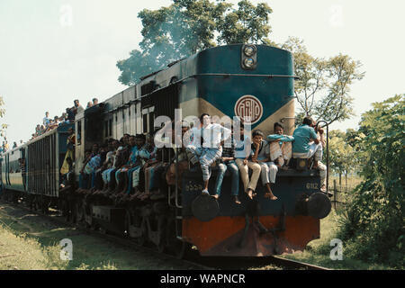 Chapai Nawabganj, Bangladesh, 2017. Un train bondé est passant par d'une station rurale à l'autre. Banque D'Images