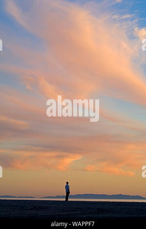 Lone figure sur la plage au coucher du soleil à Santa Monica avec vue sur la péninsule de Palos Verdes à Los Angeles, CA, USA. Banque D'Images