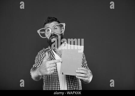 Regarder ce livre. Homme barbu à lunettes parti pointant sur cahier. Nerd étude holding livre. Le port de lunettes nerd livre de fantaisie. Étudiant universitaire avec notes de cours. Banque D'Images