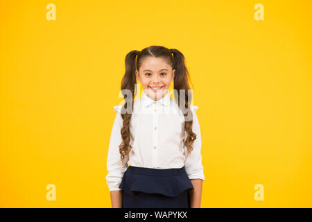 Sourire à pleines dents. Petit enfant étudiant. Élève fille sur fond jaune. Retour à l'école. Concept de vie scolaire. Célébrer la Journée de la connaissance. Fille de l'école d'émotionnel. L'obtention d'un diplôme. Heureux jour pour enfants. Banque D'Images