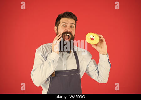 Faits sur le sucre. Aucun moyen. Barbu hippie baker tenir beigne glacé sur fond rouge. Cafe and Bakery concept. Sweet donut de Baker. Barbu homme Baker en tablier de cuisine tenir cute dessert. Banque D'Images