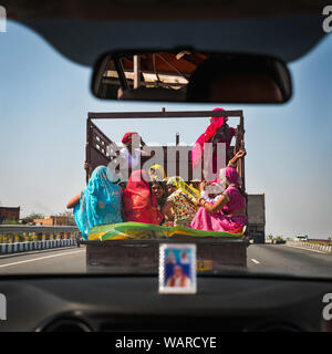 Groupe de femmes indiennes qui circule sur l'autoroute à l'arrière d'un camion, à l'extérieur de New Delhi, Inde Banque D'Images