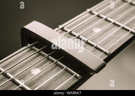 Capo noir sur la chaîne Guitare acoustique et une touche de fonction avec lumière naturelle en vue rapprochée Banque D'Images