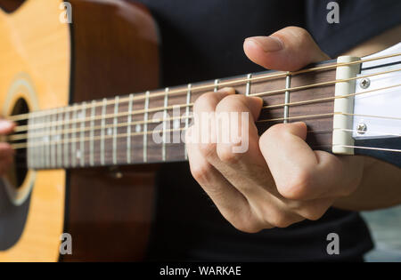 Main de joueur de guitare ou musicien part en accord de do majeur sur la corde de guitare acoustique avec un éclairage naturel en vue de côté Banque D'Images