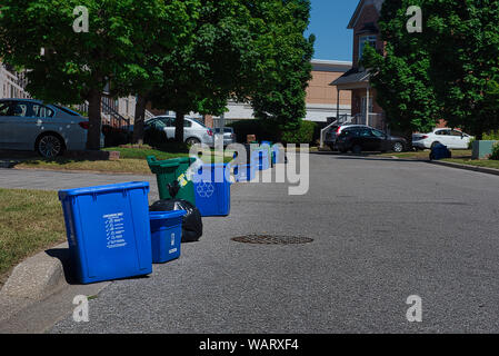 Déchets, recyclage et déchets alimentaires bacs sont en attente d'être pris en charge devant la porte de maisons sur jour de collecte. Banque D'Images