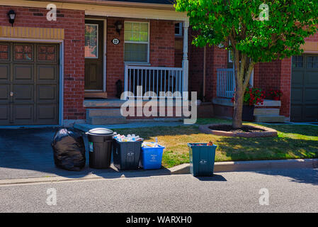 Déchets, recyclage et déchets alimentaires bacs sont en attente d'être pris en charge devant la porte d'une maison sur jour de collecte. Banque D'Images