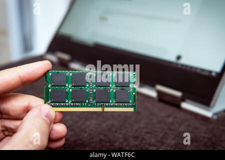 Mémoire à accès aléatoire pour le remplacement d'un ordinateur portable. Module de RAM DDR en main sur l'arrière-plan d'un ordinateur portable moderne-transformateur. ultrabook upgrade Banque D'Images