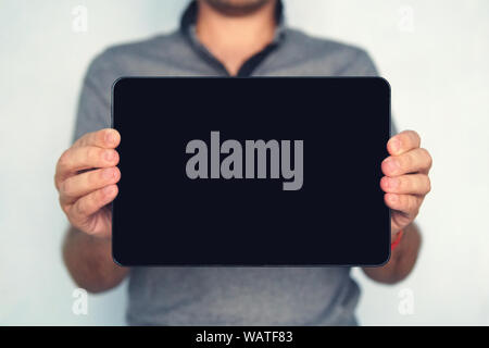Jeune homme est titulaire d'un touch pad tablet isolées sur fond blanc. Grande-taille tablette numérique avec écran noir est détenu par l'homme sur l'backro floue Banque D'Images