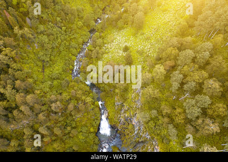 Une grande chute d'eau dans l'arrière de l'Altaï près d'une falaise abrupte avec arbres, maison jaune et toit vert. Le repos et la solitude en voyage t Banque D'Images