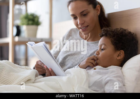 Maman et petit fils lire book in bed Banque D'Images