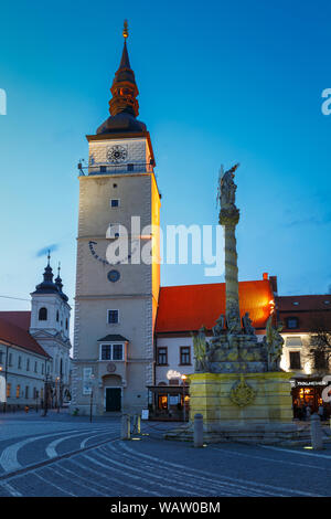 Trnava, Slovaquie - Avril 9, 2019 : tour de la ville et la Statue de la Sainte Trinité dans la place principale de Trnava, en Slovaquie. Banque D'Images