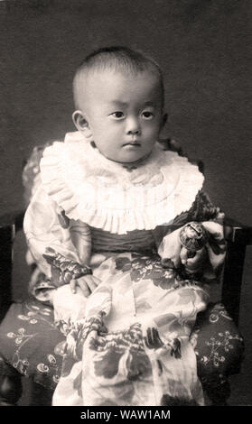 [ 1910 Japon - Bébé fille japonaise en Kimono ] - Photo de 1 ans petite fille en kimono de cérémonie. L'écriture sur la photo parle elle est née Sep 1911 (44) L'ère Meiji. Photo a été prise le Sep 17, 1912 (Taisho1). Au début du xxe siècle c'était une coutume au Japon très populaire pour prendre des photos des bébés autour de leur premier anniversaire. 20e siècle Tirage argentique d'époque. Banque D'Images